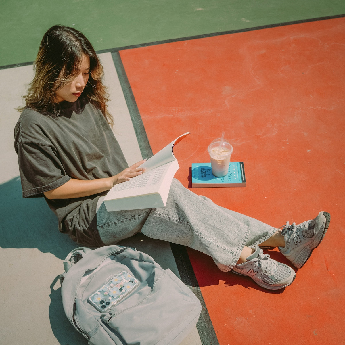 A young woman reads a book outdoors.