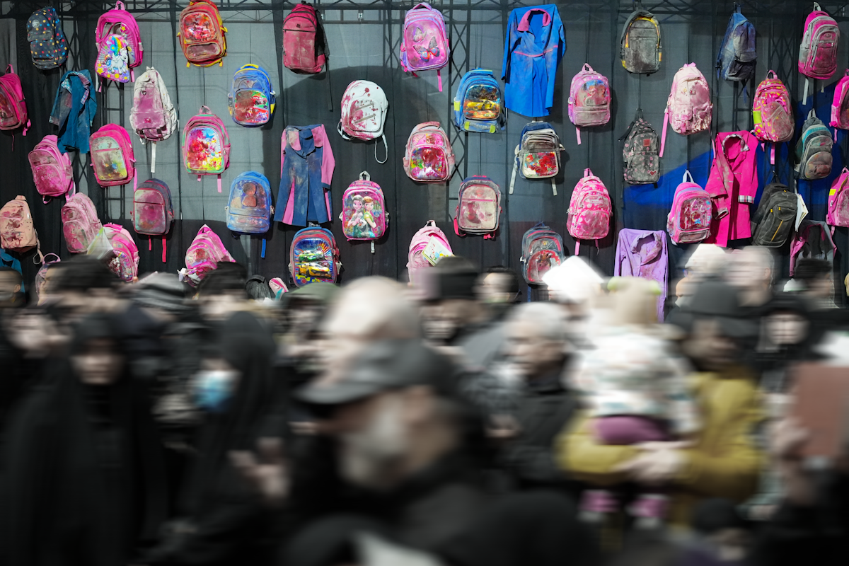 Many colorful backpacks displayed above a blurred crowd.